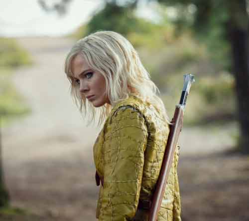 Ciri uit The Witcher loopt langs een paard op een bosweg, scene uit de Netflix-serie.