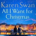 Boekomslag van All I Want for Christmas door Karen Swan, met een koppel op een bankje voor een verlichte stad tijdens de kerst.