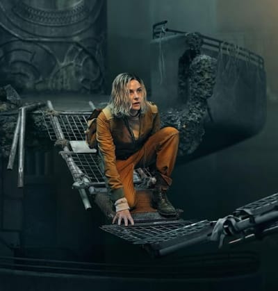 Juliette uit de Silo serie op Apple TV+, zittend in een kapotte structuur binnen de mechanische wereld van de silo.
