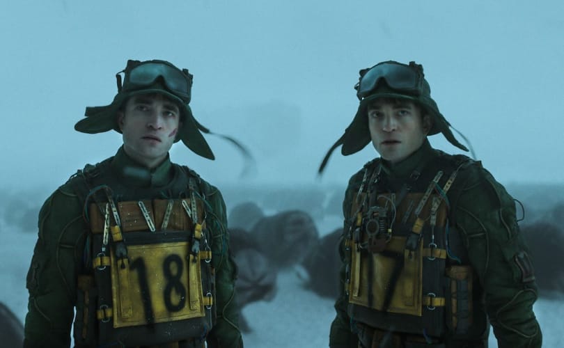 Scène uit de film Mickey 17, met twee identieke personages in winterse militaire kleding op een besneeuwd landschap.