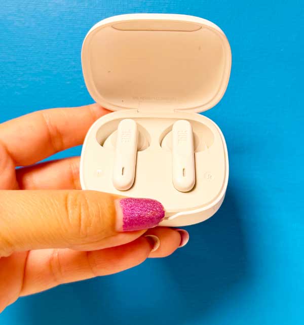 Witte JBL-oortjes in open oplaadcase, vastgehouden in een hand